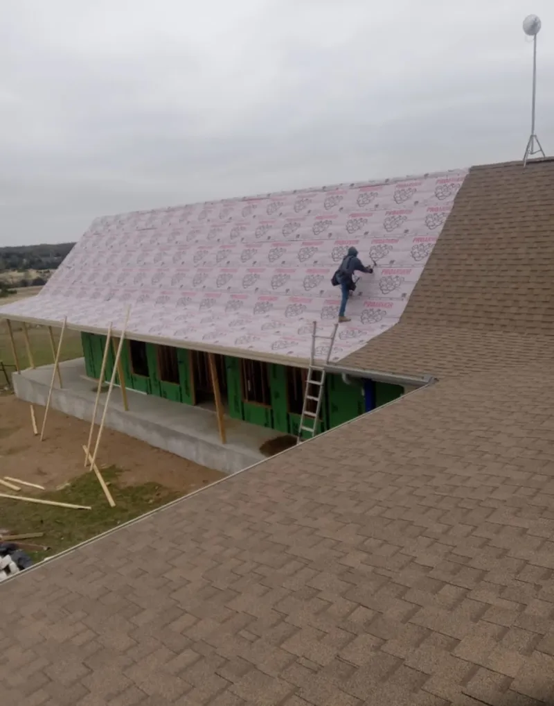 Worker preparing underlayment for a metal roof installation in Sturbridge